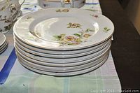 Stack of 8 white Lynmore fine china dinner plates with delicate rose pattern and gold rim.
