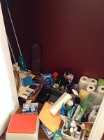 Overview showing assorted cleaning supplies including paper towels, spray bottles, sponges, and other containers, with some storage items.