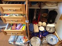 Photo of three open wooden drawers revealing kitchen supplies including plastic wrap and bags