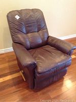 Front angled view of brown leather recliner showing overall seat, backrest, and armrests.