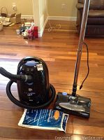Full view of Dirt Devil vacuum canister with hose, wand, and vacuum bags on floor.
