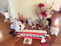 Wide shot displaying all items in the lot spread on the floor including floral arrangements, candles, stuffed animals, glassware and wrapping paper