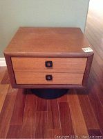 Front view of a wooden night stand with two drawers and square black handles, showing condition and overall design.