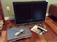 Toshiba Regza LCD TV and Samsung dual VCR/DVD player placed on hardwood floor. Accessories including remote and cords visible.