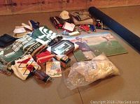 Wide view of all items showing golf blankets, hats, book, sweaters, framed print, pillow, weights.