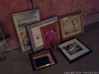 Collection of seven framed prints and art pieces placed on floor, including an 8x10 lady in water print and smaller art pieces.