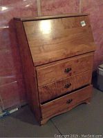 Front view of the wooden secretary desk closed, showing its rectangular shape and wood finish.