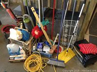 Photo showing assorted cleaning tools including brooms, mop bucket, light bulbs, extension cords, and a Bravetti toaster oven.