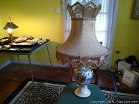 Photo of Victorian china lamp with fabric fringe shade showing its size and decorative base.