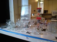 Assortment of stemmed wine glasses, martini glasses, Tuscany aperitif glasses, and other glassware arranged on a table.
