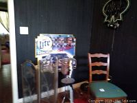 Overall view showing fire screen, chair, Miller Lite neon sign, and metal ice chest