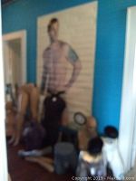 Blurry photo showing various mannequin legs, torsos and a large Mundo Unico poster hung on blue wall.