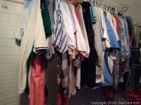 Photo of assorted men's tees and short-sleeved shirts hanging on a rack showing different colors and styles including stripes and solids
