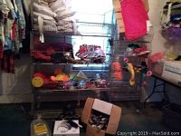 Wide view of wire metal racks holding assorted purses, party favor items, and fabric items, showing overall lot contents.