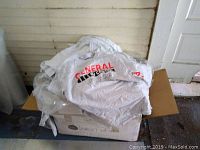 Closed box and pile of grey advertising T-shirts with 'General RV center' logo partially visible