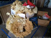 Photo of the lot showing the large beige wreath with gold ribbons, beige garland, red Santa hats, and boxed Jingle Bells set along with additional boxed decor items