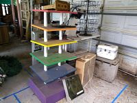 Homemade multicolored wood shelving with some dirt, older cooler boxes, and a box-style fan