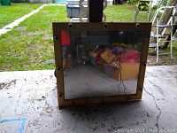 Square theatrical makeup mirror with bulb sockets seen from the front, placed on the ground outside with a grass background