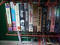 Close-up photo showing a row of VHS tapes including Airplane, Annie Hall, and others in a red wire rack