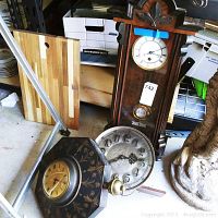 Photo showing three clocks: a tall grandfather-style clock, a round clock, and an octagonal floral wooden clock.