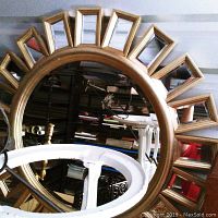 Photo of entire sunburst wall mirror showing round central mirror and surrounding rectangular mirrored segments with gold-tone frame.