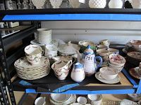 Wide shot showing the entire set on a shelf including the lidded serving bowl, multiple cups, bowls, plates, teapot, creamer, and miniature stein.