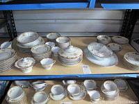Wide view of stacked dinnerware including platters, plates, bowls, saucers, and cups on shelving