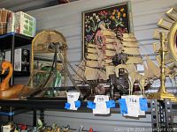 Seven decorative items displayed on shelf including metal giraffe, brass candlestick, metal bust, Bull and Bear sculptures, wooden duck, and glass globe on metal stand.