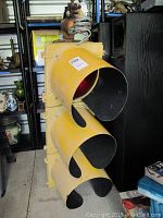 Angled full view of yellow metal three-light traffic signal housing with visors