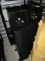 Two black Klipsch speakers side by side in storage unit