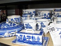 Blue and white ceramic dishes grouped showing a lidded serving bowl, butter dish with lid and base, coffee pot, sugar canister, teapot, and mugs with blue floral and oriental patterns.