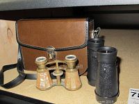 Three binoculars displayed: Bushnell binoculars with brown leather case, plastic binoculars, and vintage Verdi mother of pearl inlay binoculars.