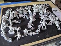 Photo showing multiple pewter miniature figurines spread on black surface, various fantasy RPG characters including wizards and fighters