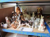 Shelf showing a collection of various ceramic dog figurines in different sizes and colors.