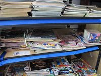 Stacks of vintage Marvel comic books on blue metal shelving showing multiple issues and titles