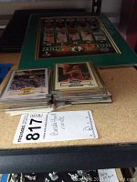Framed Celtics 4-photo collage and stacks of basketball cards on a table with a MaxSold lot sticker showing description as basketball cards.