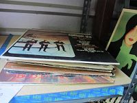 Stack of vinyl records showing multiple album covers, slightly worn edges