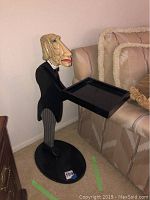 Side view of the full butler figurine side table with tray, displayed next to a couch