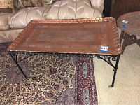 Rectangular copper tray style topped table placed on patterned rugs with adjacent furniture visible, showing full view of the table and its size scale.