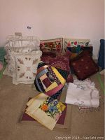 Various handmade pillows and covers laid on the floor including embroidered floral and patchwork designs.