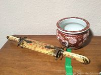 Photo showing the full carving set with decorated sheath and the hand painted vase placed behind it on a wooden surface.