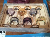 Set of five vintage cordial glasses with colored bowls and twisted clear stems in a wooden box