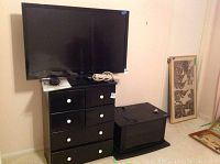 LG 41 inch TV sitting on top of a black TV stand with a black dresser next to it (dresser not included).