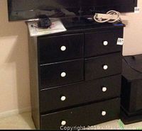 Full view of the vintage black painted dresser showing six drawers with white ceramic knobs.