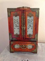 Full front view of the jewelry box showing the two carved jade panel doors with metal fittings and the bottom drawer handle.