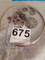 Photo showing entire collection of sterling silver jewelry including necklace, ring, three pins, and earrings.