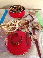 Collection of several costume jewelry items including necklaces, watches, copper bracelet, and pins on a table