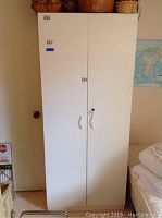 Front view of closed white cabinet with two doors and white handles.