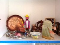 Photo showing large hammered copper tray, Asian decorative plate, wooden figurine, pottery vases, carved stone sculptures.