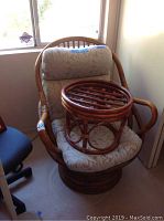 Rattan swivel chair with floral cushion seat and backrest with small round rattan stool on it